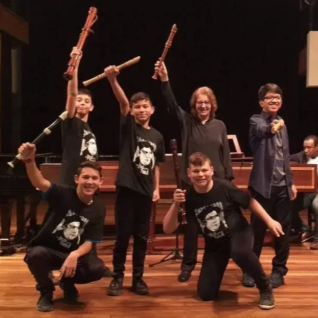 Integrantes comemoram no palco com as flautas erguidas