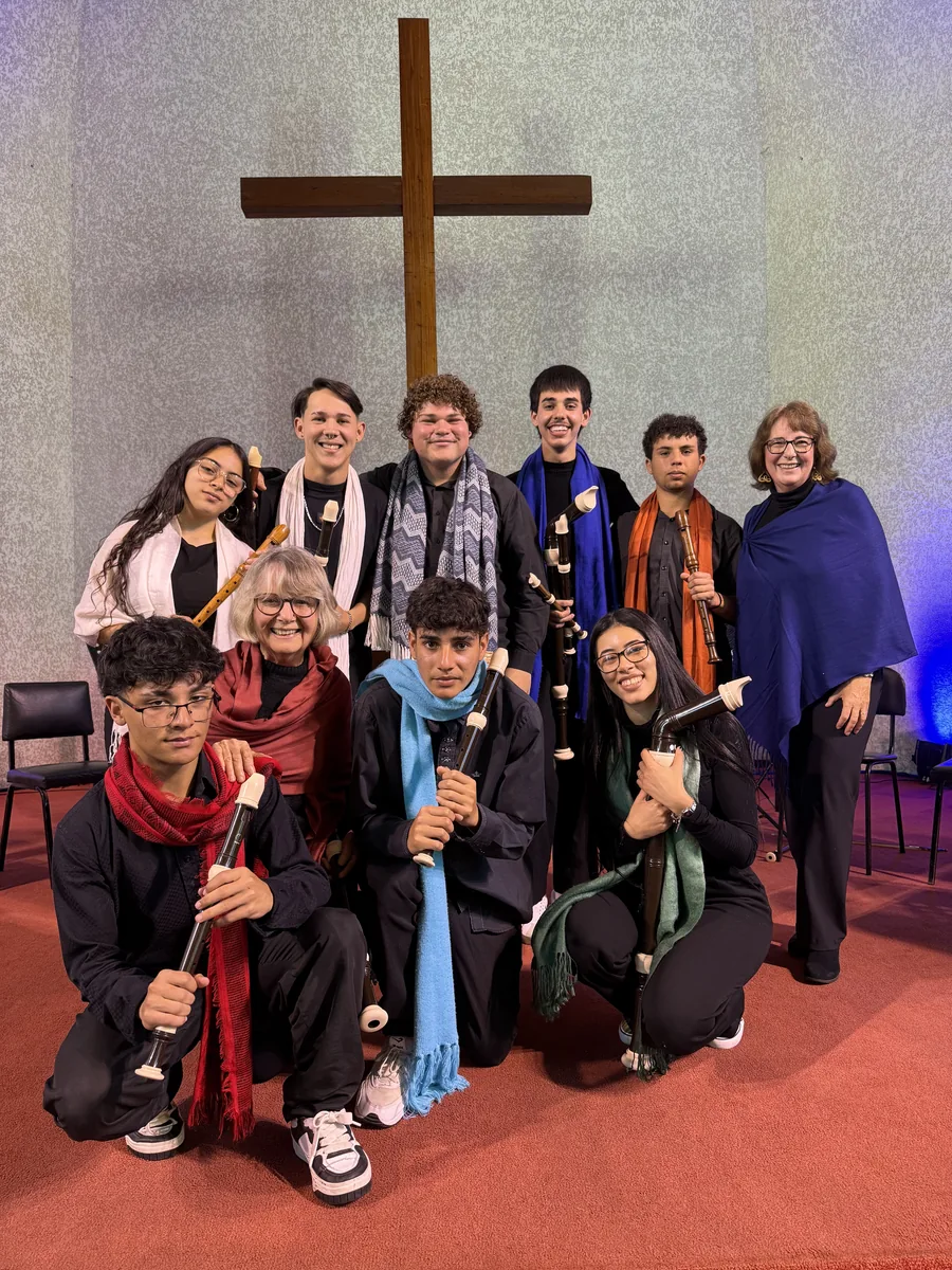 Foto do grupo com cachecóis coloridos diante da cruz
